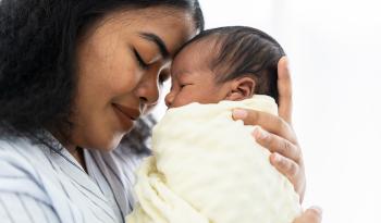 Mother resting forehead on newborn baby