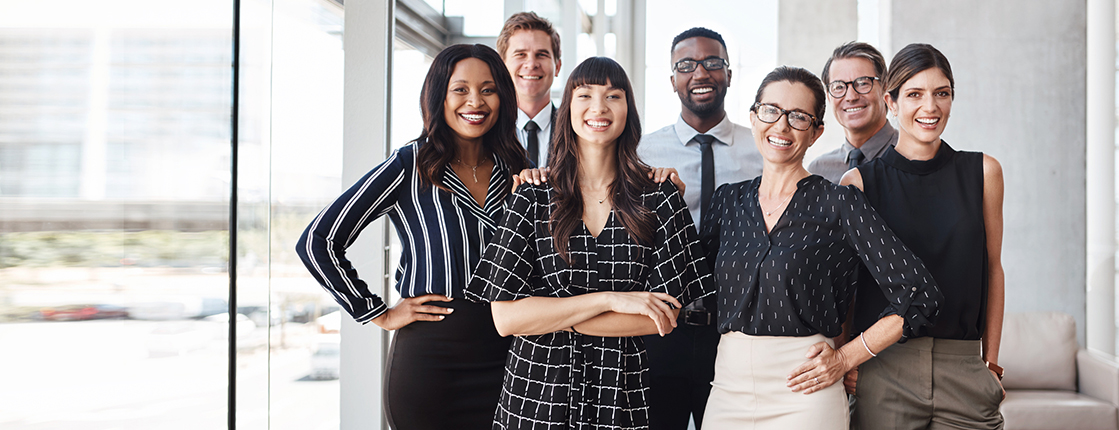 7 people standing together in an office smiling