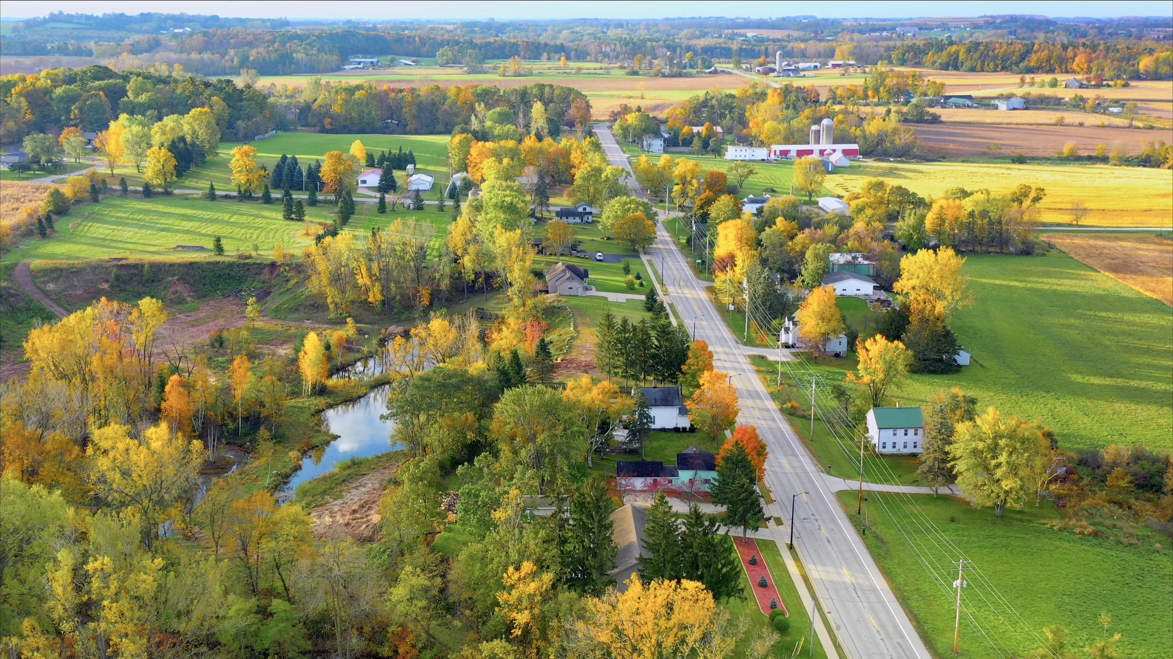 Rural town with one road, few houses, changing leaf colors outside