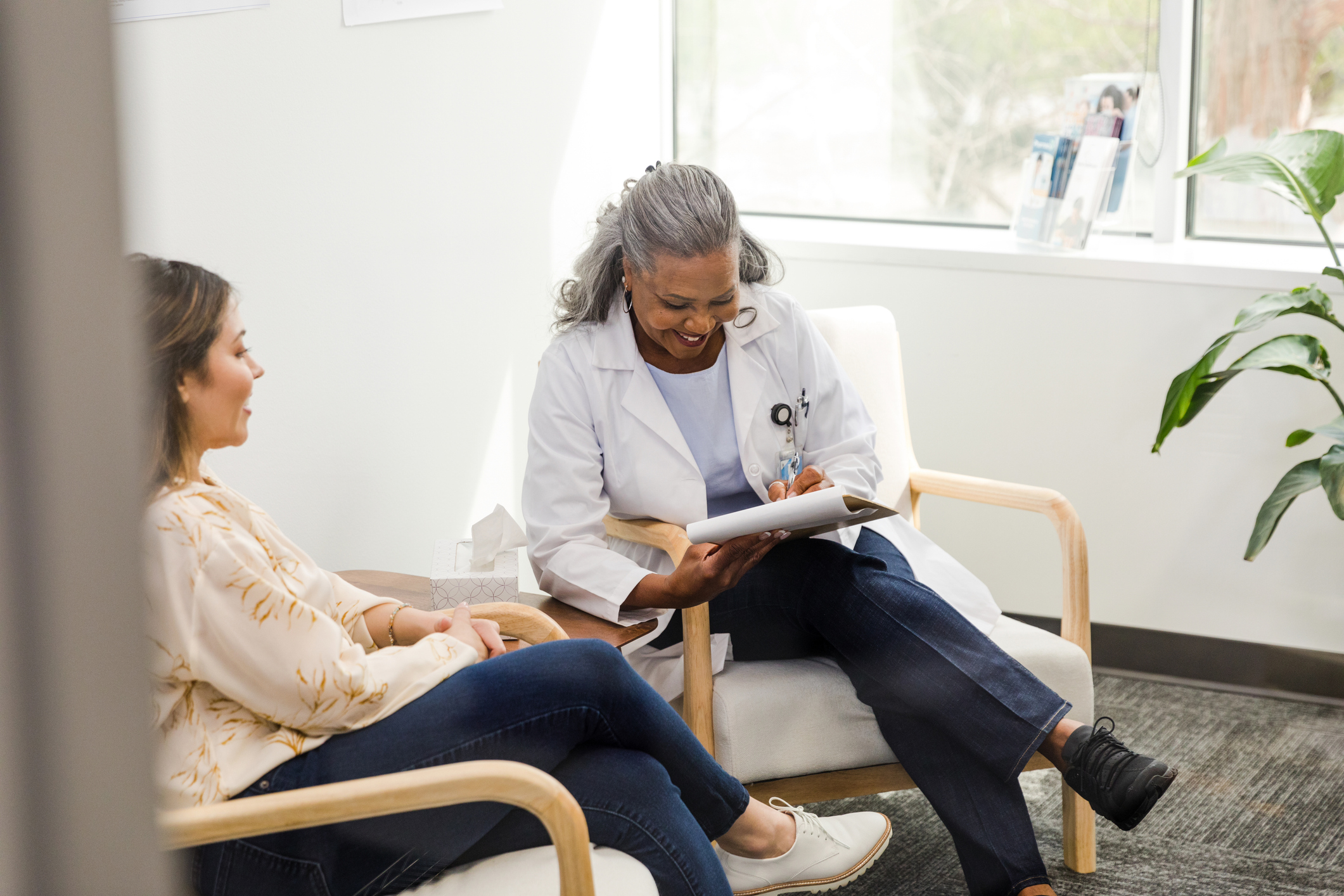 Older female doctor laughing with female patient