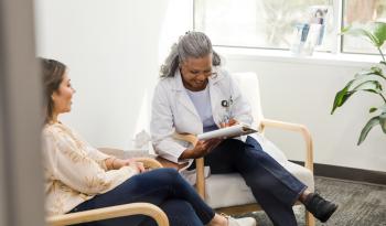 Older female doctor laughing with female patient